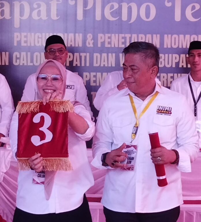 Pasangan calon Bupati dan Wakil Bupati Barru, Andi Ina Kartika Sari dan Andi Abustan AB, tersenyum sambil menunjukkan nomor urut 3 yang mereka dapatkan dalam Pilkada Barru 2024, dalam rapat pleno terbuka di Kantor KPU Barru, 23 September 2024.